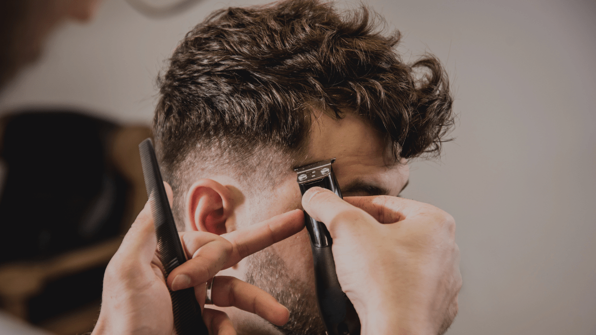 Einem Mann werden die Haare mit einem Rasiere geschnitten.