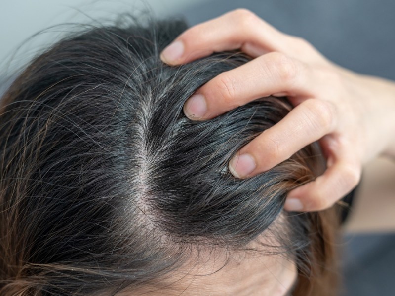 Eine Frau fasst sich in die langen, braunen Haare.