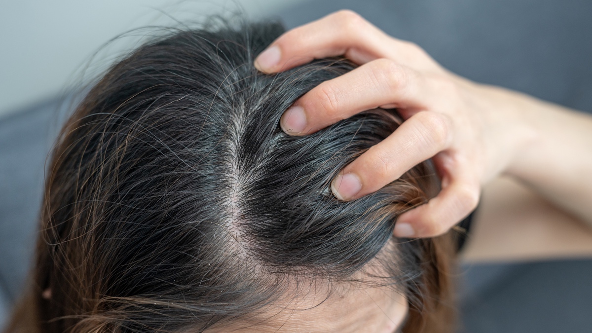 Eine Frau fasst sich in die langen, braunen Haare.