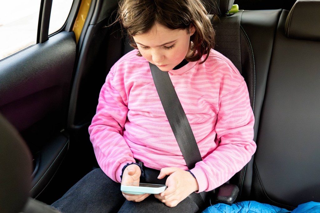 Mädchen mit Smartphone im Auto