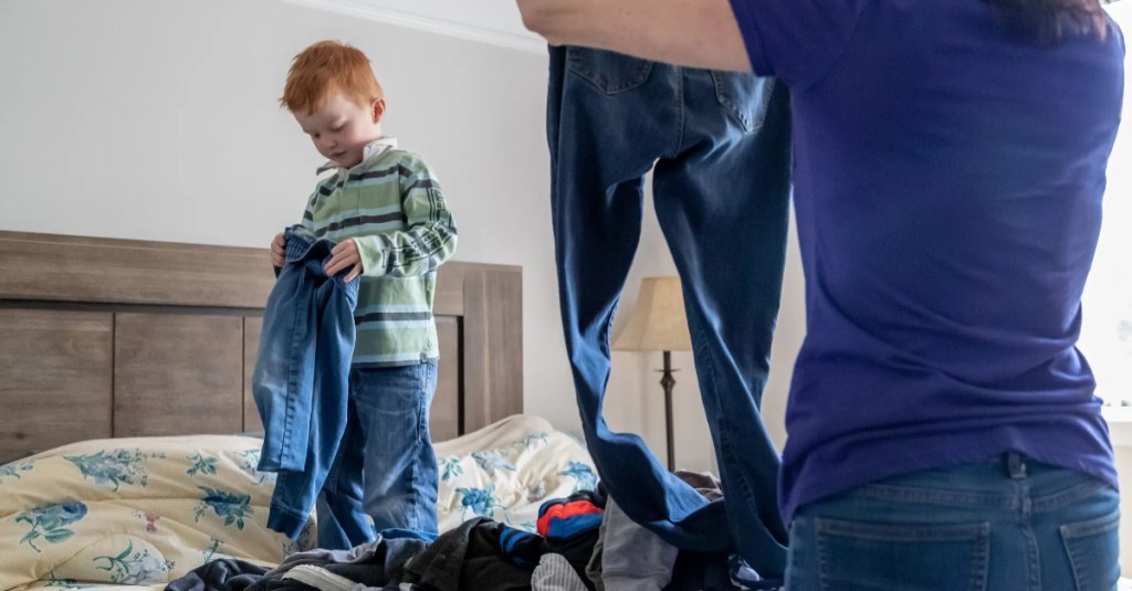 Kind steht auf Bett sortiert Wäsche