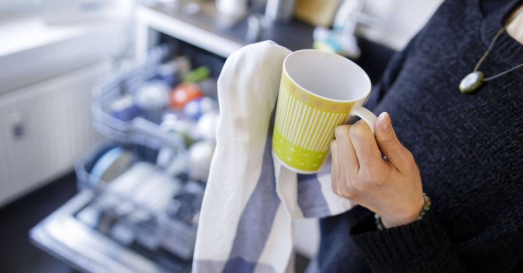 Tasse wird mit Geschirrhandtuch abgetrocknet