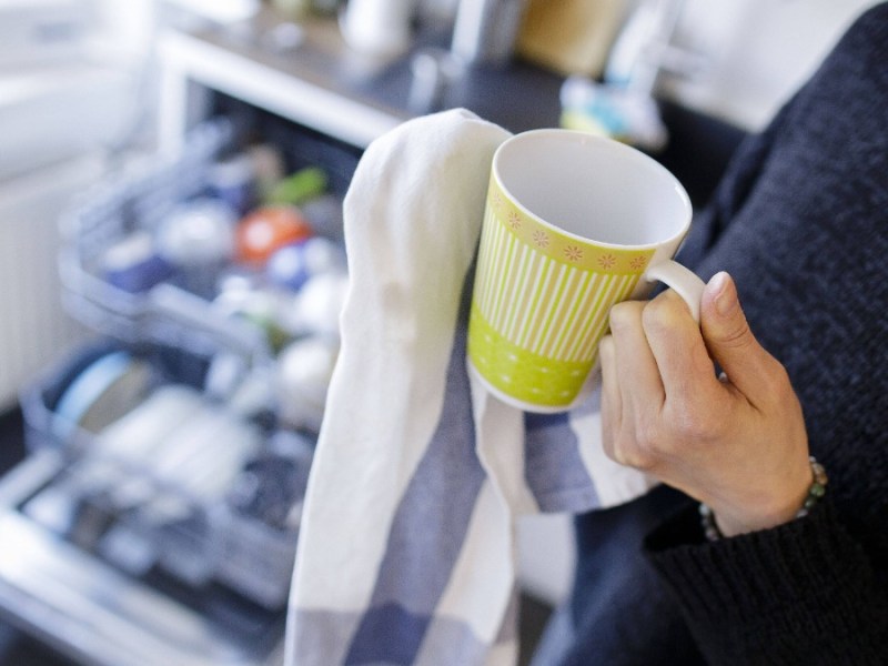 Tasse wird mit Geschirrhandtuch abgetrocknet