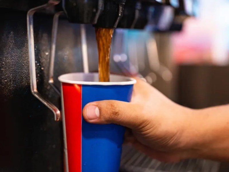 Cola läuft aus einem Automaten in einen Becher