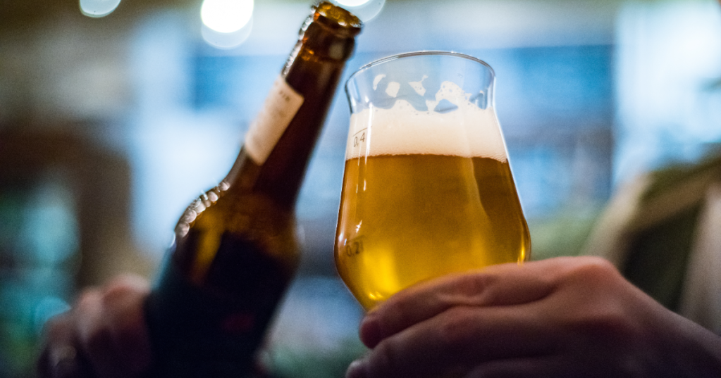 Person schenkt Bier aus Flasche in ein Glas.