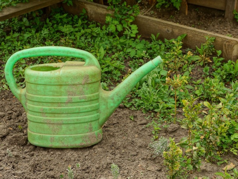 Verdreckte Kunststoff-Gießkanne im Garten