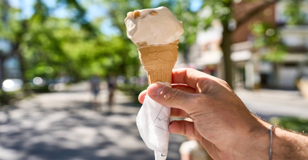 Jemand hält ein Eis in der Waffel in der Hand.