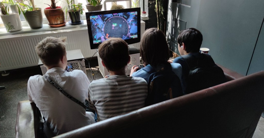 Vier Jungs sitzen auf der Couch und spielen ein Videospiel