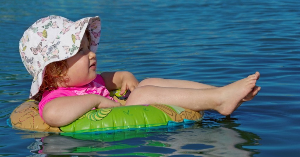 Kleines Mädchen schwimmt auf einem Schwimmreifen im Wasser