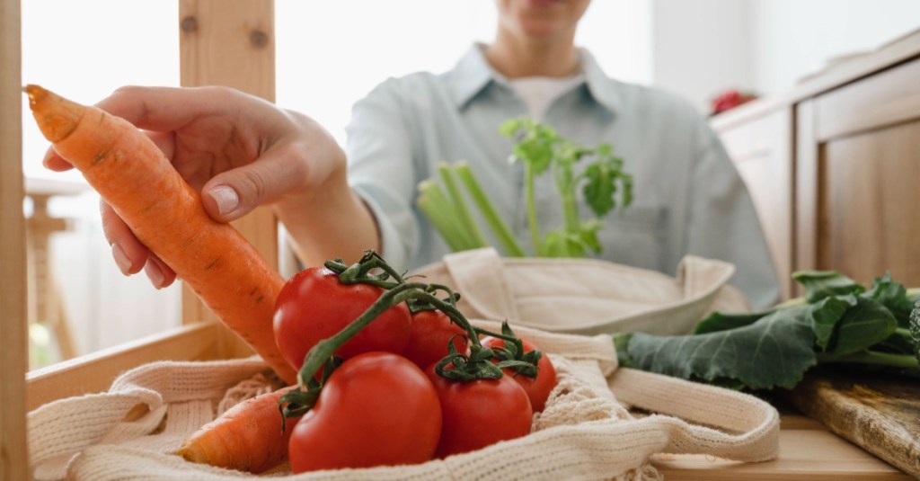 Eine Frau greift nach einer Möhre und Tomaten