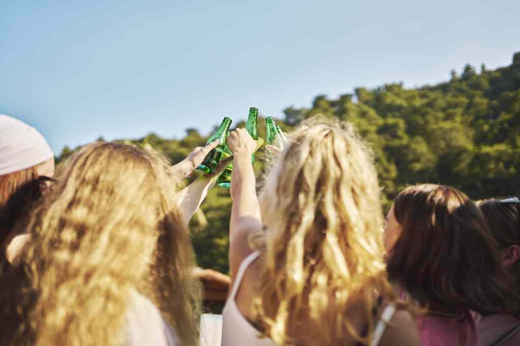 Junge Menschen stoßen in der Sonne an mit Bier.