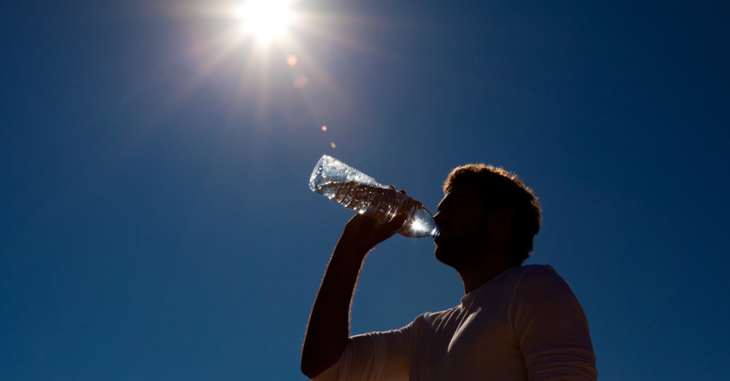 Mann trinkt Wasser aus Flasche unter Sonne