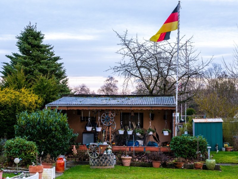 Eine Deutschlandflagge an einem Fahnenmast in einem Schrebergarten