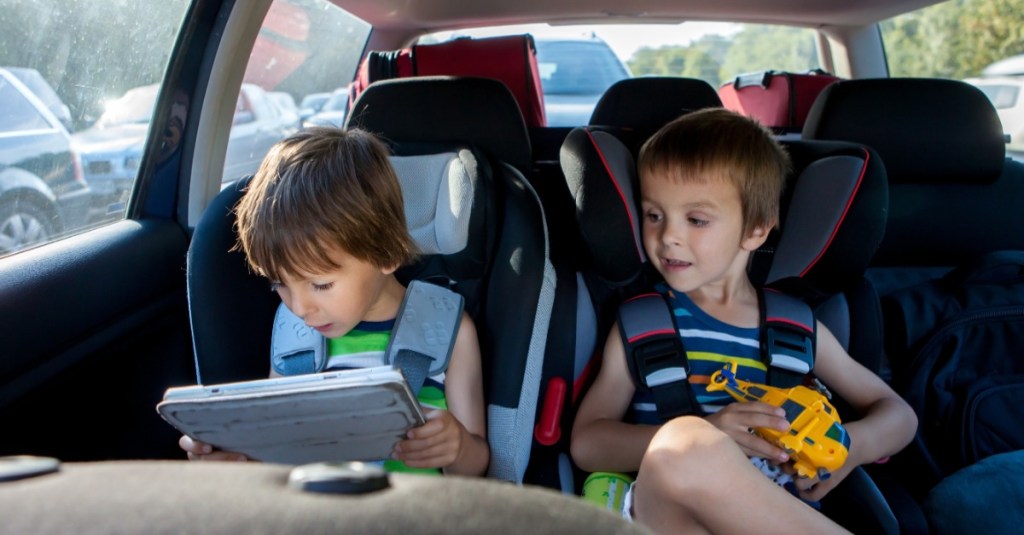 Zwei Jungs sitzen im Auto, einer von ihnen hält ein Tablet in der Hand