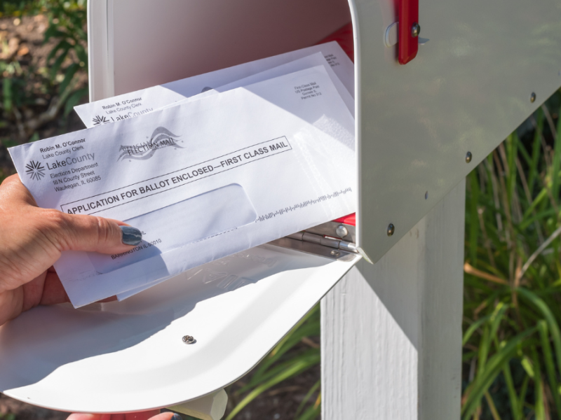 Eine Person holt Post aus dem Briefkasten.