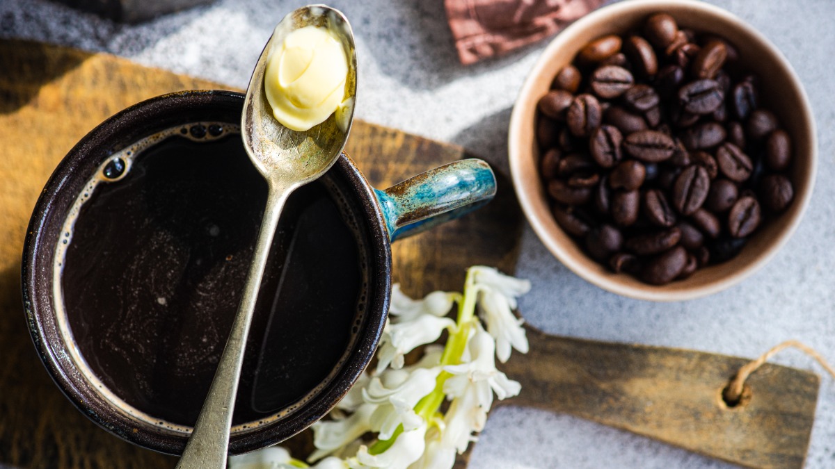 Auf einer Tasse Kaffee liegt ein LÃ¶ffel mit etwas Butter