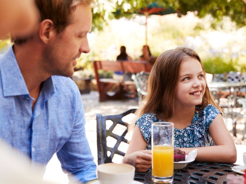 Eine Familie sitzt am Tisch mit Kaffee und Kuchen