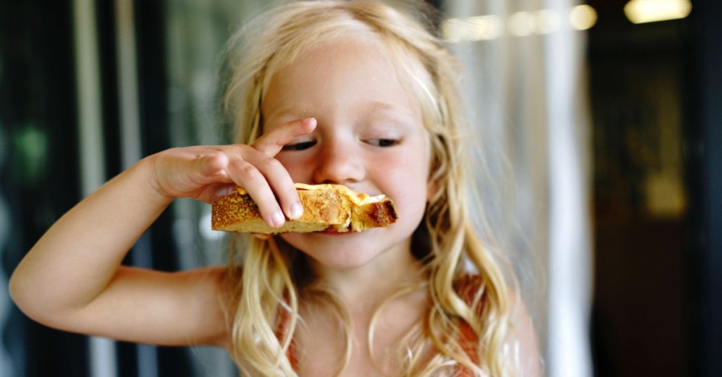 Blondes Mädchen isst eine Scheibe Brot