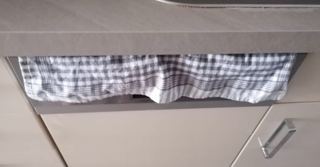 ein Handtuch hängt über der Klappe der Spülmaschine