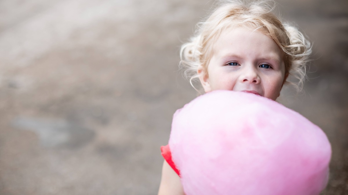 Kleines Mädchen hält pinke Zuckerwatte in den Händen