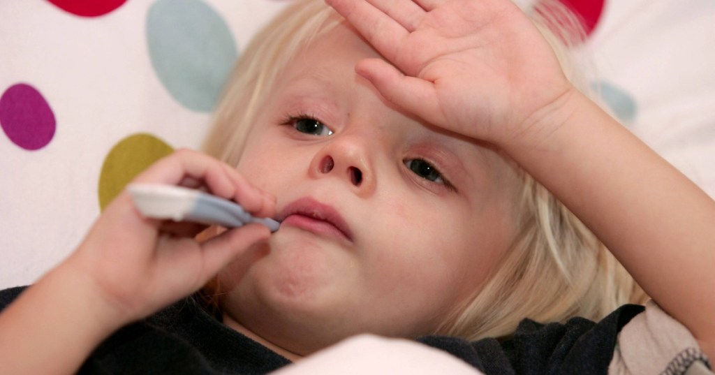 kleiner blonder Junge liegt krank im Bett