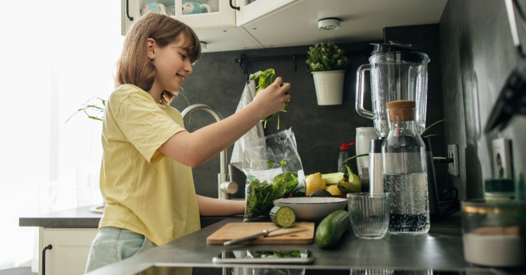 Ein Mädchen mixt sich einen gesunden Smoothie