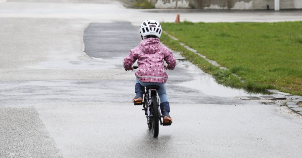 Kind fährt alleine mit einem Fahrrad auf der Straße