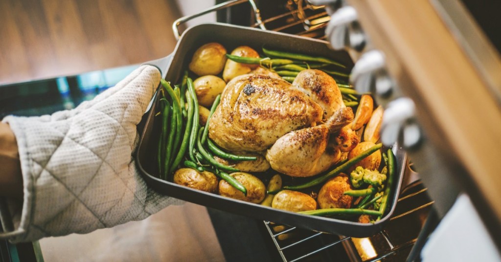 Ein Hähnchen wird in einer Form in den Backofen geschoben