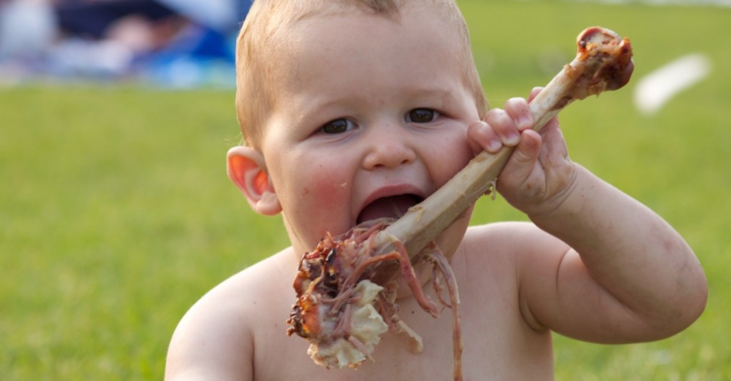 Ein Baby nagt an einer gegarten Truthahnkeule