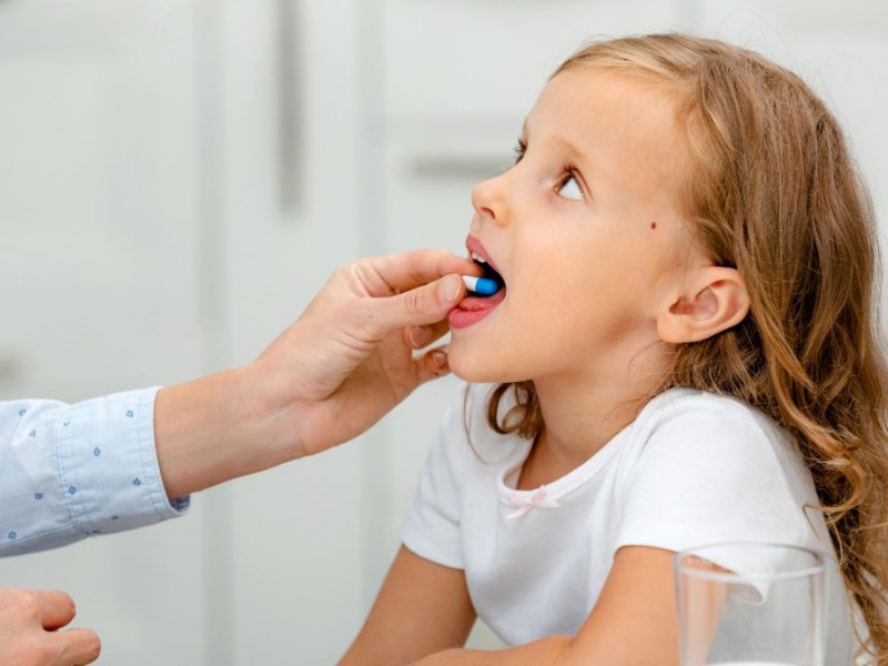 VitaminprÃ¤parate fÃ¼r Kinder: Ein MÃ¤dchen hat eine Tablette im Mund