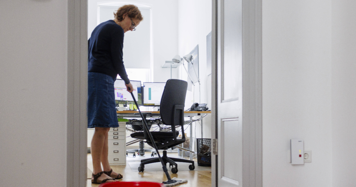 Frau putzt den Boden eines BÃ¼ros.