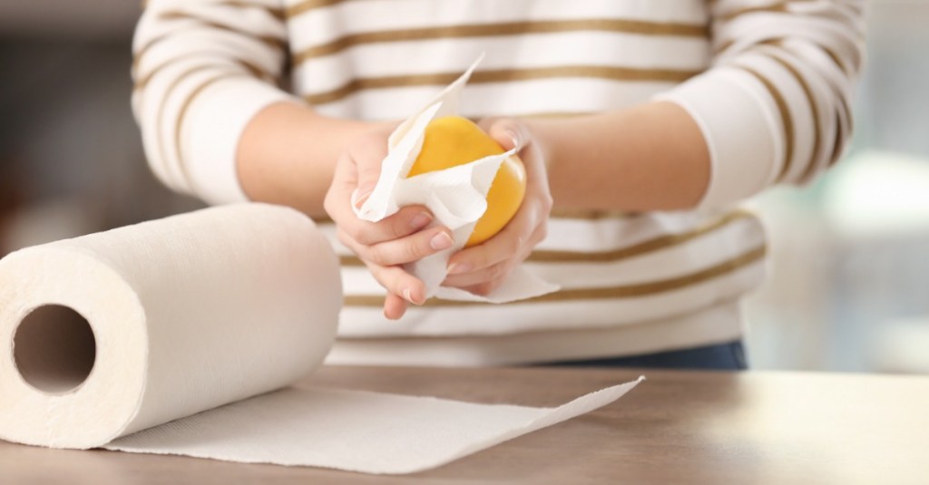 eine Frau wischt einen Apfel mit Küchenrolle ab