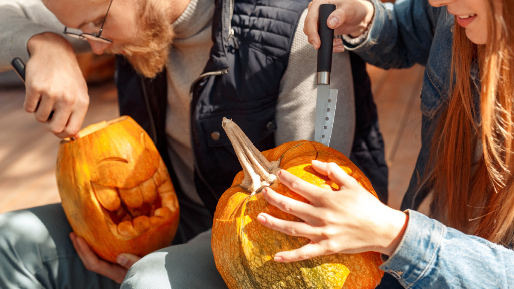 Ein Mann und eine Frau schnitzen je einen Halloween-Kürbis.