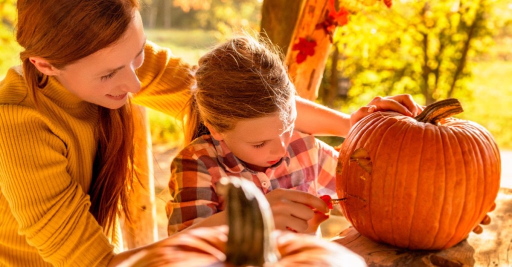 Mutter schnitzt mit Tochter einen Halloween-Kürbis.