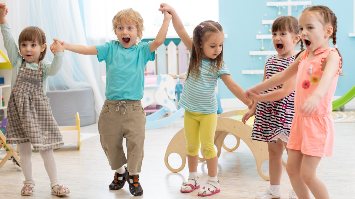 eine Gruppe frÃ¶hlicher Kinder tanzt im Kindergarten