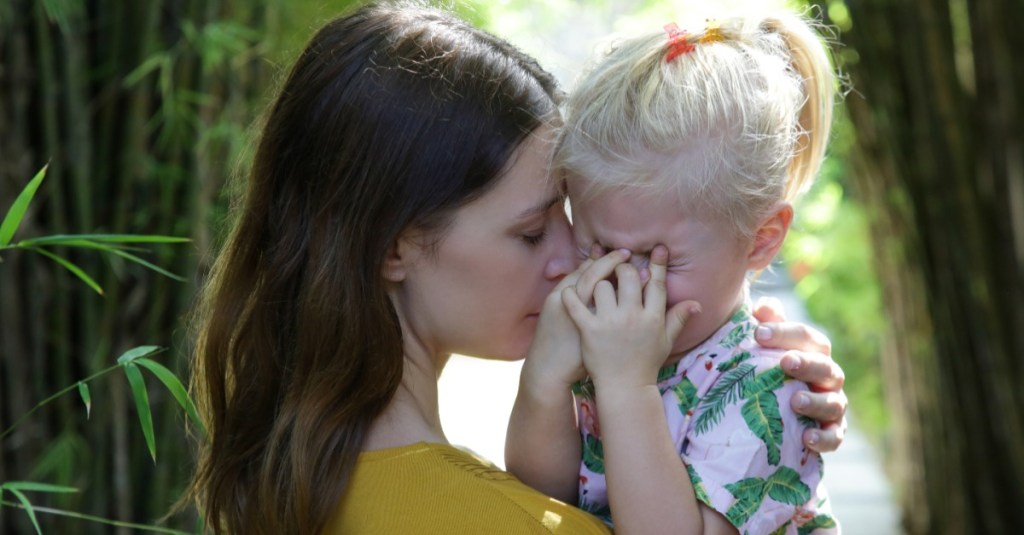 eine junge Mutter tröstet ihr weinendes Kind