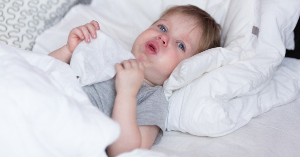 kleiner Junge liegt mit Keuchhusten im Bett