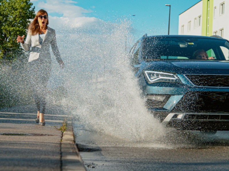 Auto fÃ¤hrt durch PfÃ¼tze und spritzt eine FuÃŸgÃ¤ngerin nass