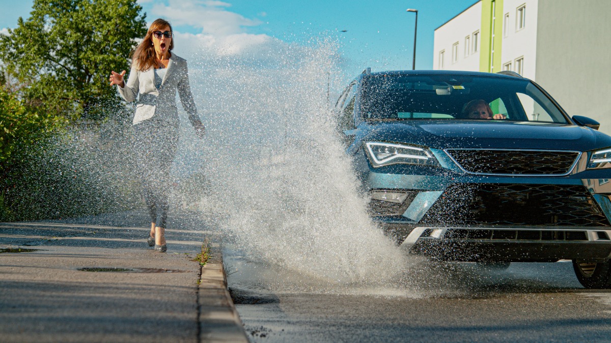 Auto fÃ¤hrt durch PfÃ¼tze und spritzt eine FuÃŸgÃ¤ngerin nass