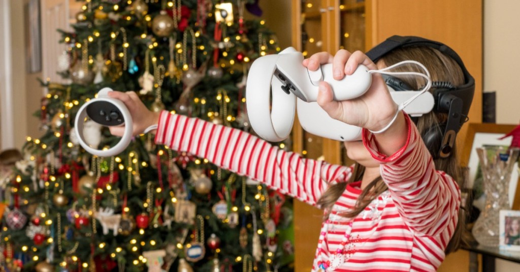 kleines Mädchen steht mit einer VR-Brille vor dem Weihnachtsbaum