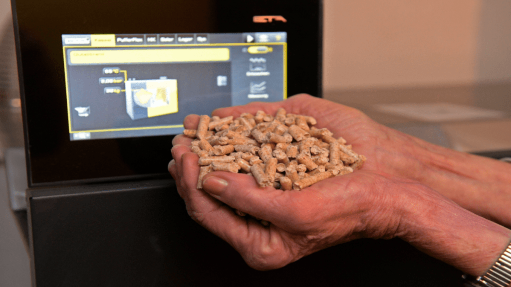 Eine Hand hält viele kleine Pellets aus Holz.