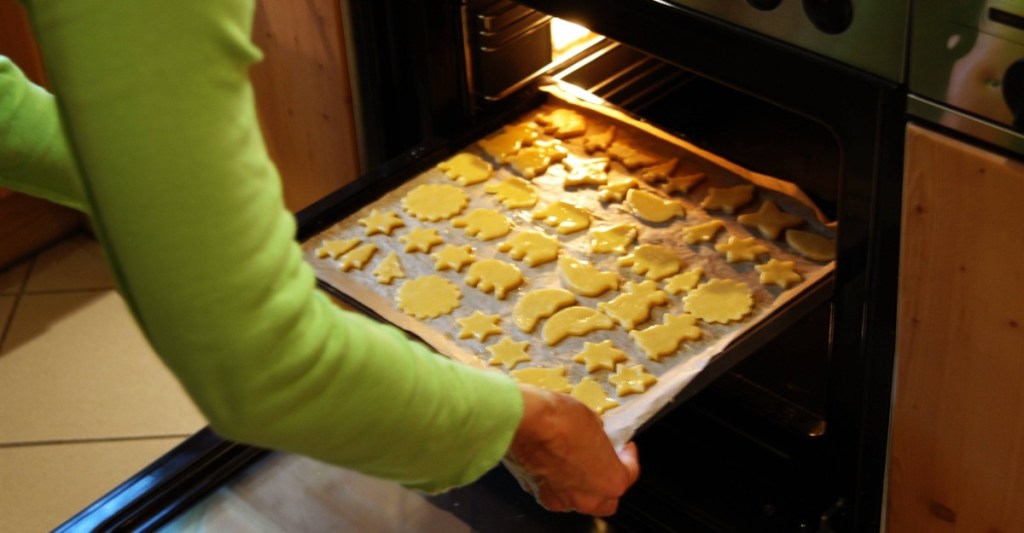 Plätzchen backen: Plätzchen backen: Ein Backblech mit Plätzchen wird in den Ofen geschoben