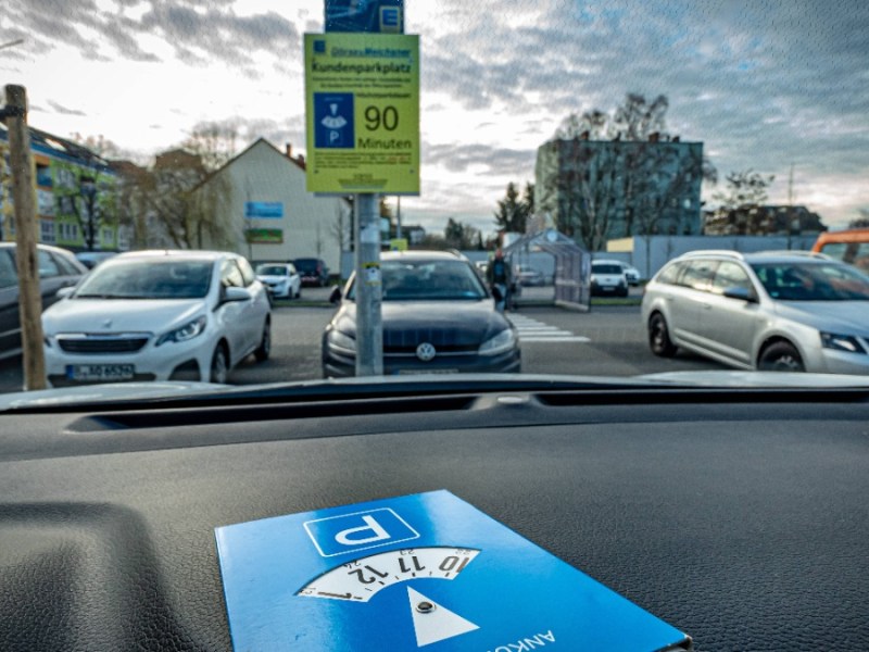 ein Auto steht auf einem Parkplatz, hinter der Windschutzscheibe ist eine Parkuhr