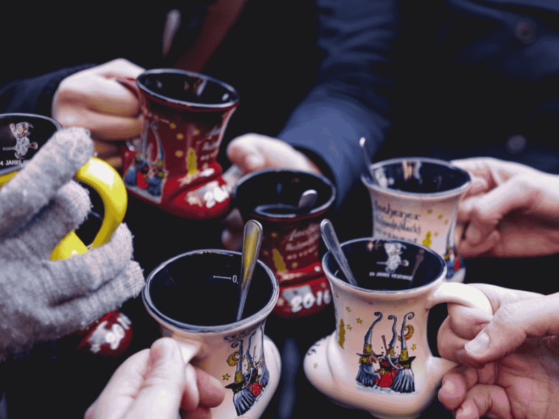 Weihnachtsmarkt, Leute stoßen mit Punsch an.