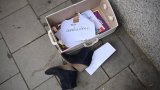 Eine „Zu verschenken“-Kiste am Straßenrand mit Büchern und Schuhen.