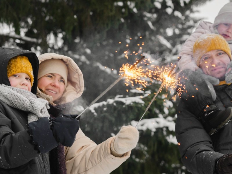 NeujahrsvorsÃ¤tze: Eltern erfreuen sich mit ihren zwei Kindern an brennenden Wunderkerzen