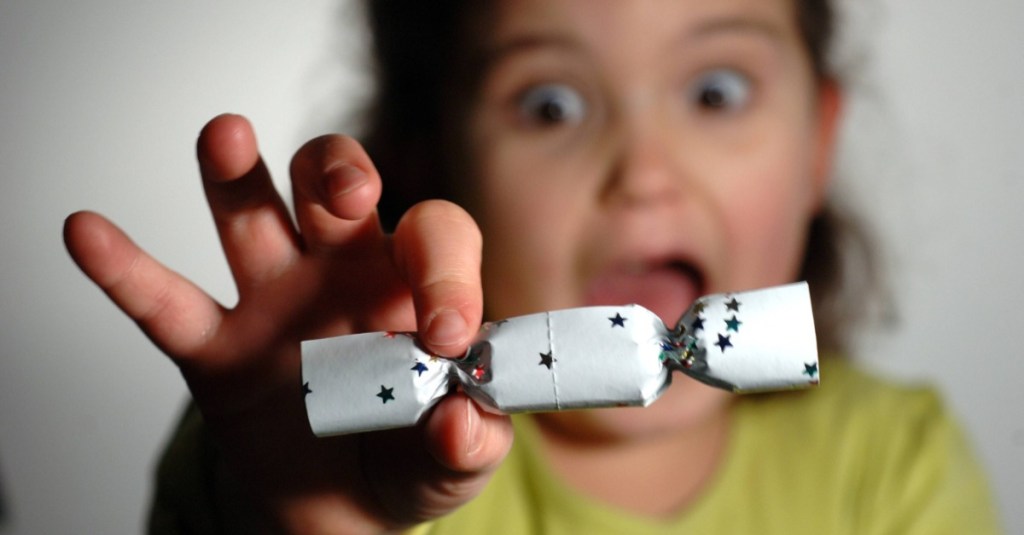 Silvester mit Kindern: ein Mädchen hält einen Knallbonbon in die Kamera