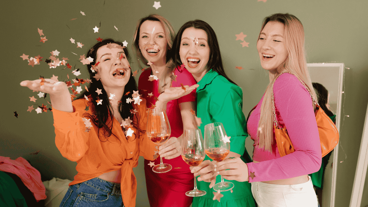 Galentine's Day, bunt gekleidete Frauen stoßen an und werfen Konfetti