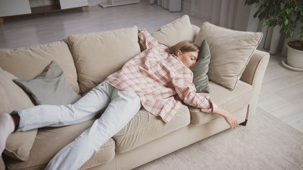 Eine Frau liegt erschöpft auf einer Couch.