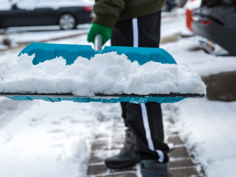 Schnee räumen: Ein Anwohner befreit mit einem Schneeschieber einen Gehweg von Schnee